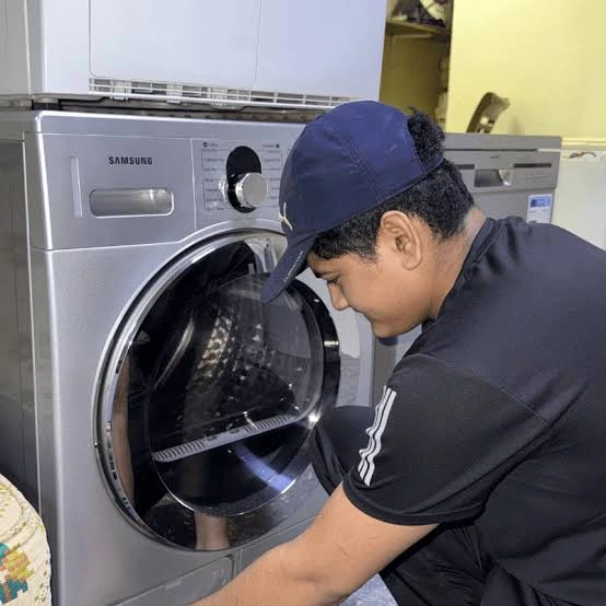 Technician servicing a silver front-loading washing machine